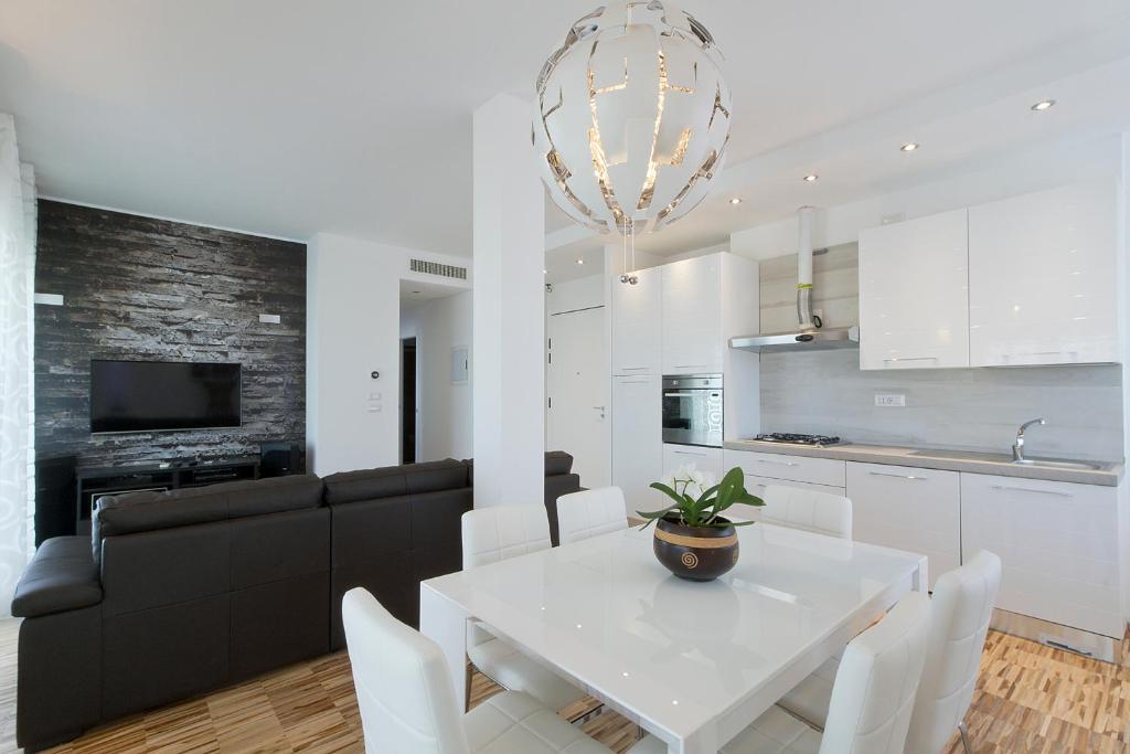 米萨诺阿德里亚蒂科Attico Stema Luxury的厨房以及带白色桌椅的起居室。