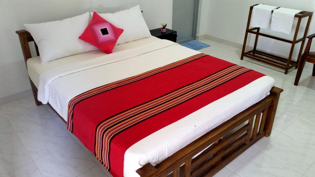 波隆纳鲁沃拉达旅客之家旅馆的一张床上的床上红色枕头
