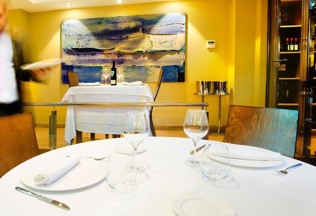 奥维多坎波阿莫酒店的一张桌子,上面有酒杯和绘画