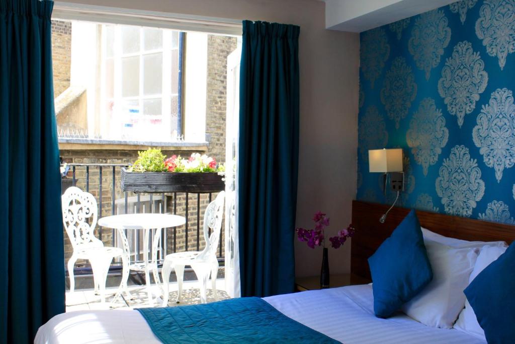 伦敦警长酒店的一间卧室配有一张床,阳台配有桌椅
