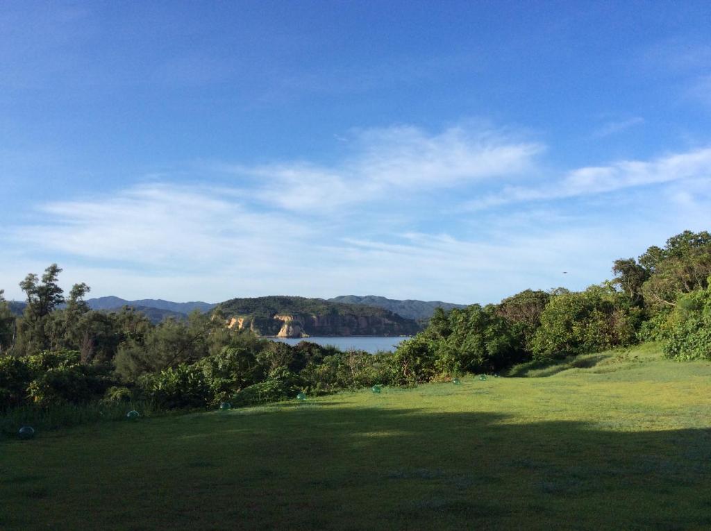 西表岛玛雅古斯库度假酒店的绿色的田野,有湖泊背景