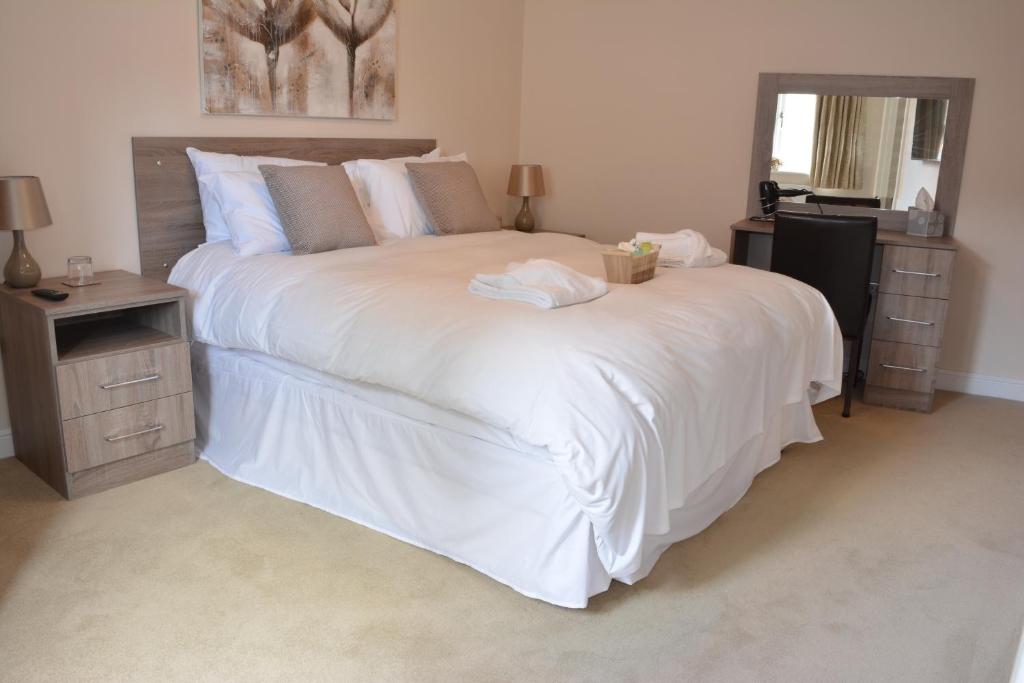 Winterborne KingstonGreyhound Inn的卧室配有一张白色大床和镜子