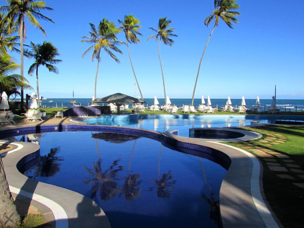 普拉亚多Residencial Bali Bahia Apto Alto Padrão BATUR 106的棕榈树和大海的游泳池