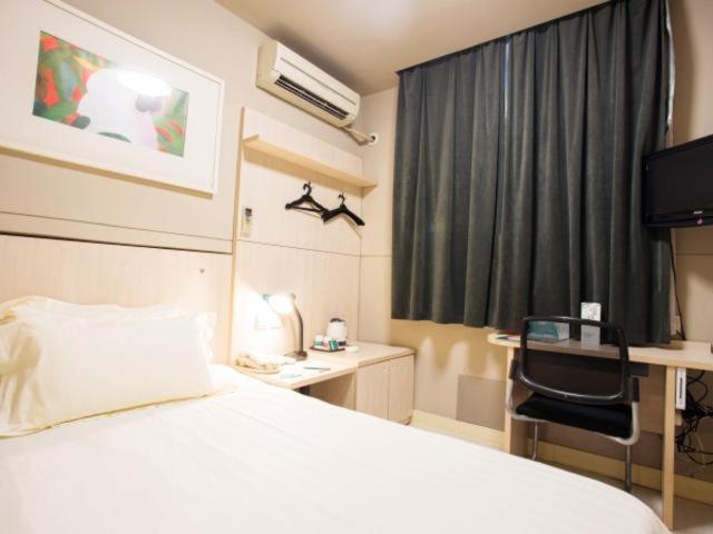 嘉定锦江之星上海嘉定城中路酒店的卧室配有白色的床、书桌和窗户。