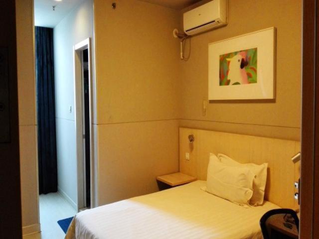 徐州锦江之星徐州金鹰国际购物中心夹河东街酒店的卧室配有白色的床,墙上挂着一幅画
