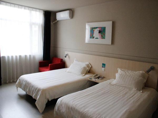 成都锦江之星成都杜甫草堂酒店的酒店客房,设有两张床和一张红色椅子