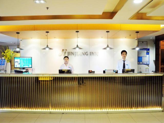 苏州锦江之星苏州火车站北广场酒店的三个男人站在餐厅柜台后面