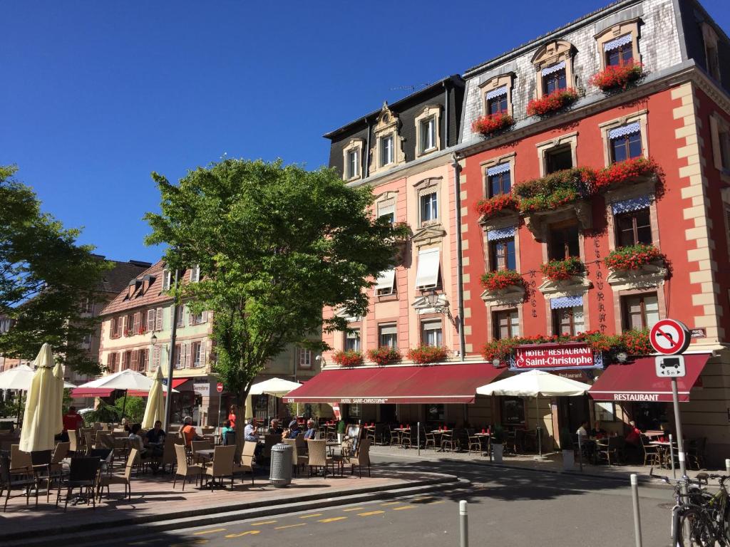 贝尔福Hotel-Restaurant St-Christophe的建筑前方一条带桌椅的街道