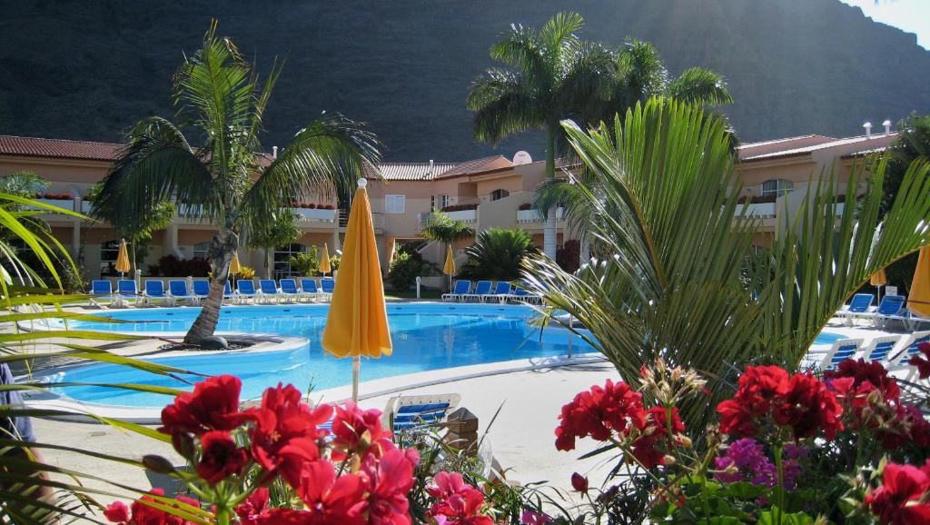 巴耶格兰雷伊詹都德尔孔德公寓酒店的酒店游泳池设有黄色遮阳伞和棕榈树