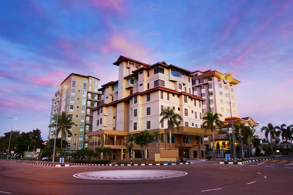 斯里巴加湾市D安格乐可服务式公寓的一条街道前方有棕榈树的大建筑