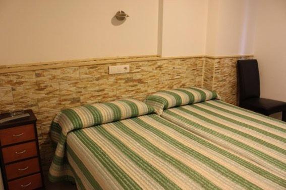 阿尔贝尔达德里瓜德里瓜山谷旅馆的一间卧室配有一张带绿条纹被子的床