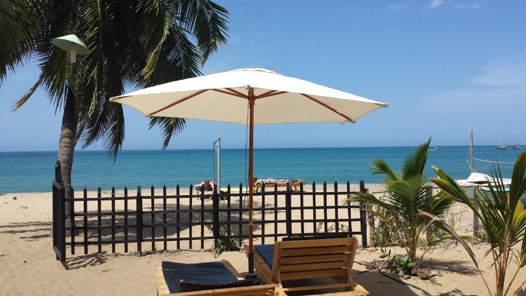 阿鲁甘湾Etnico Surf Resort的海滩上带两把椅子和一把遮阳伞的海滩