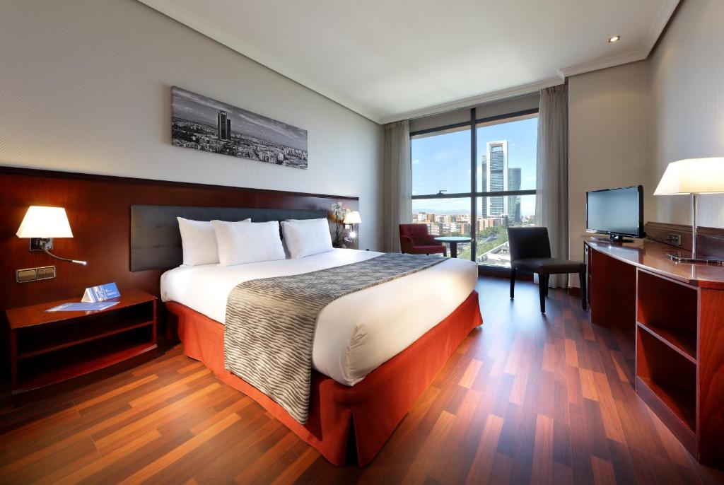 马德里Crisol Vía Castellana的酒店客房配有一张床、一张书桌和一台电视。