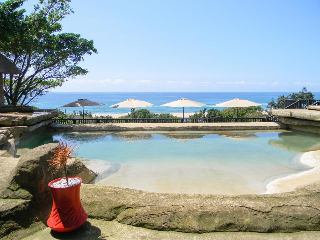 Elysium糖海滩度假酒店的海滩上带遮阳伞的大型水池