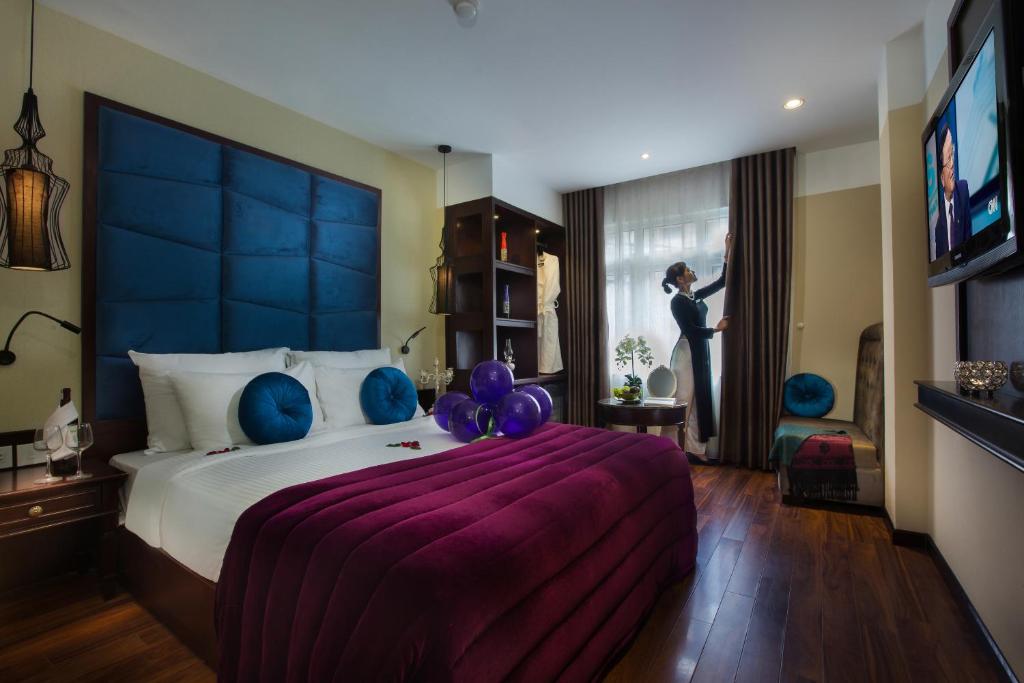 河内Ambassador Hanoi Hotel & Travel的一间卧室配有一张带气球的大床,另一位女士则眺望窗外。
