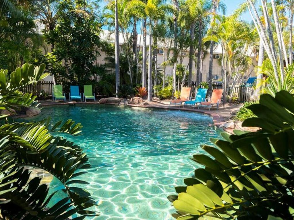赫维湾赫维湾海滩汽车旅馆的一个带蓝色椅子的游泳池,棕榈树