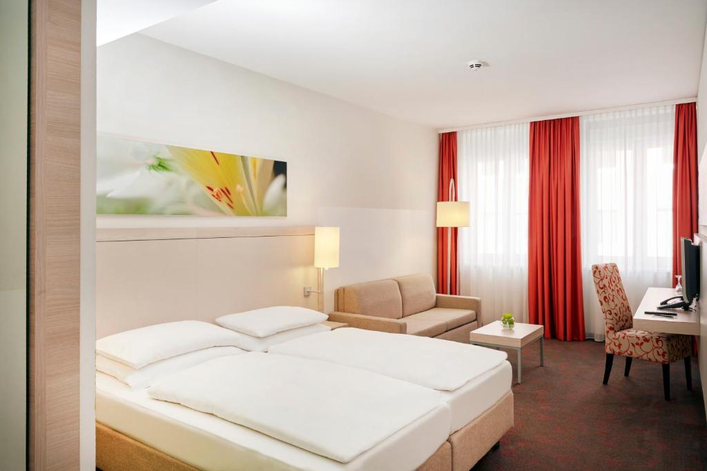 慕尼黑慕尼黑H+酒店的配有一张床和一张书桌的酒店客房