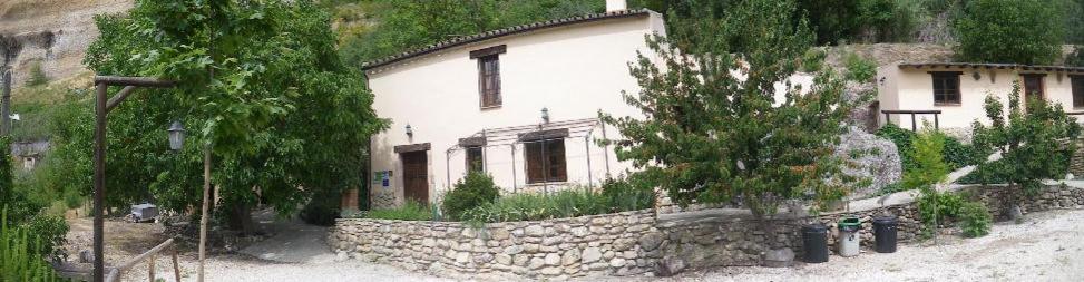 隆达Huerta del Tajo的一栋白色房子,旁边是一座石墙