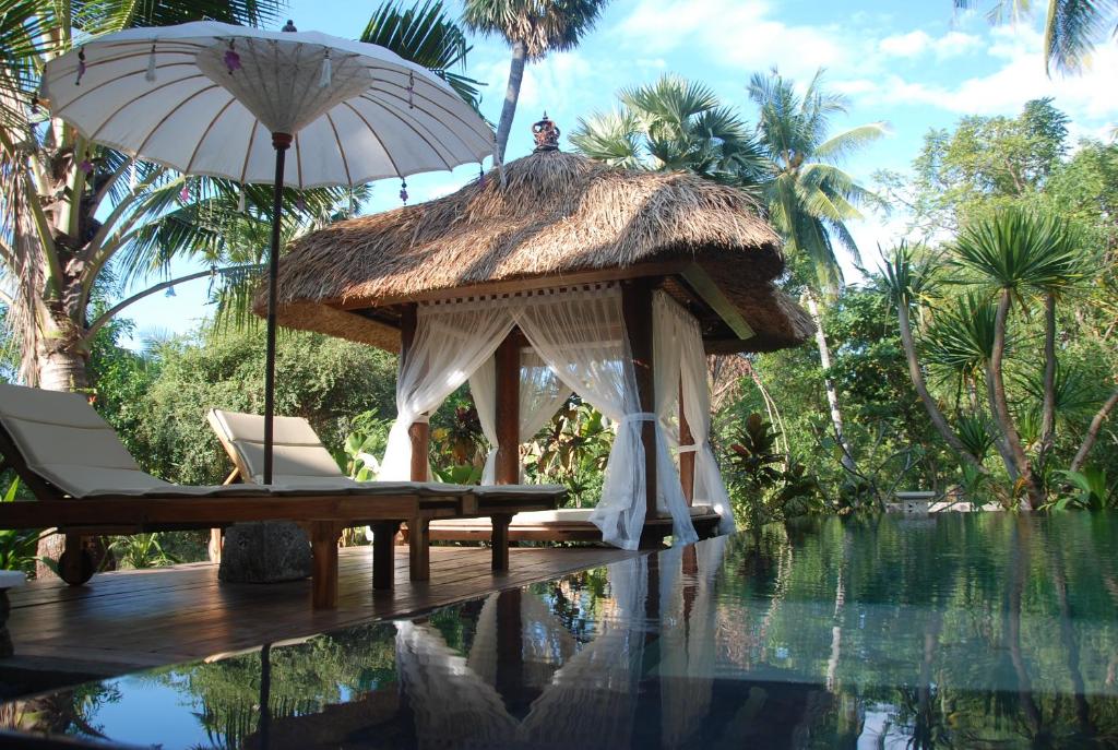 特贾库拉奥克托帕斯别墅的游泳池旁的凉亭配有椅子和遮阳伞