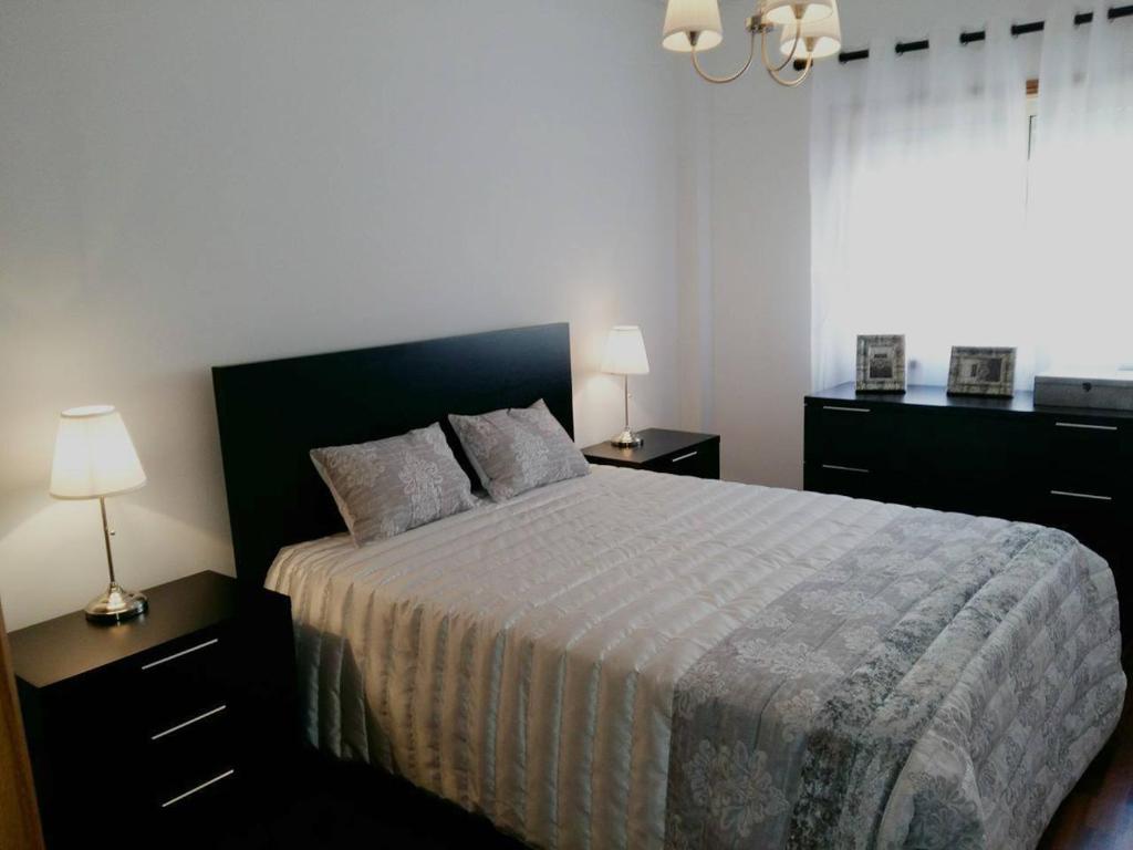 阿威罗Lovely Apartment Aveiro的一间卧室配有一张带两盏灯的床和一扇窗户。