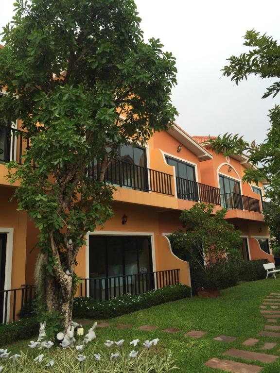 呵叻萨塔别墅精品度假村 的一座橘色的建筑,前面有一棵树