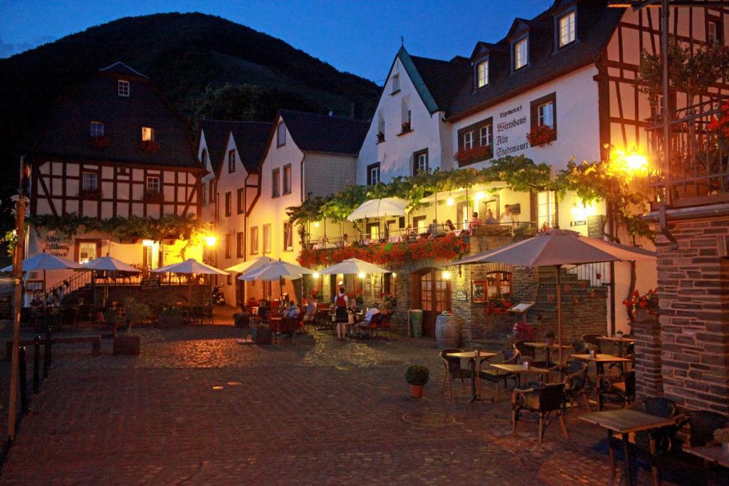 拜尔施泰因Hotel Restaurant Alte Stadtmauer的一群晚上带桌子和遮阳伞的建筑