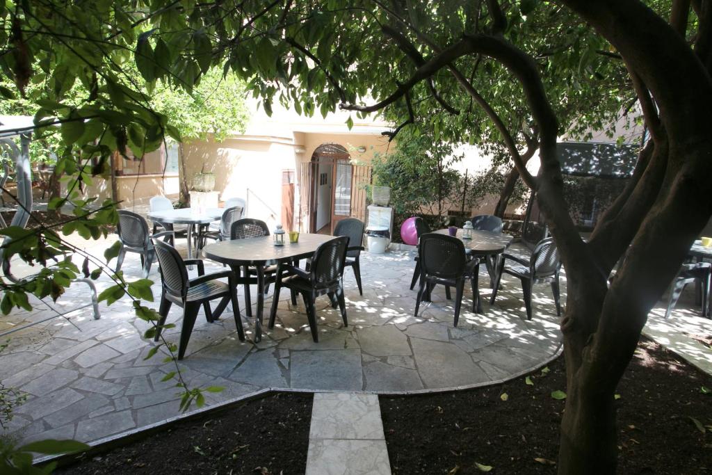 罗马New Generation Hostel Rome Center的树下带桌椅的庭院