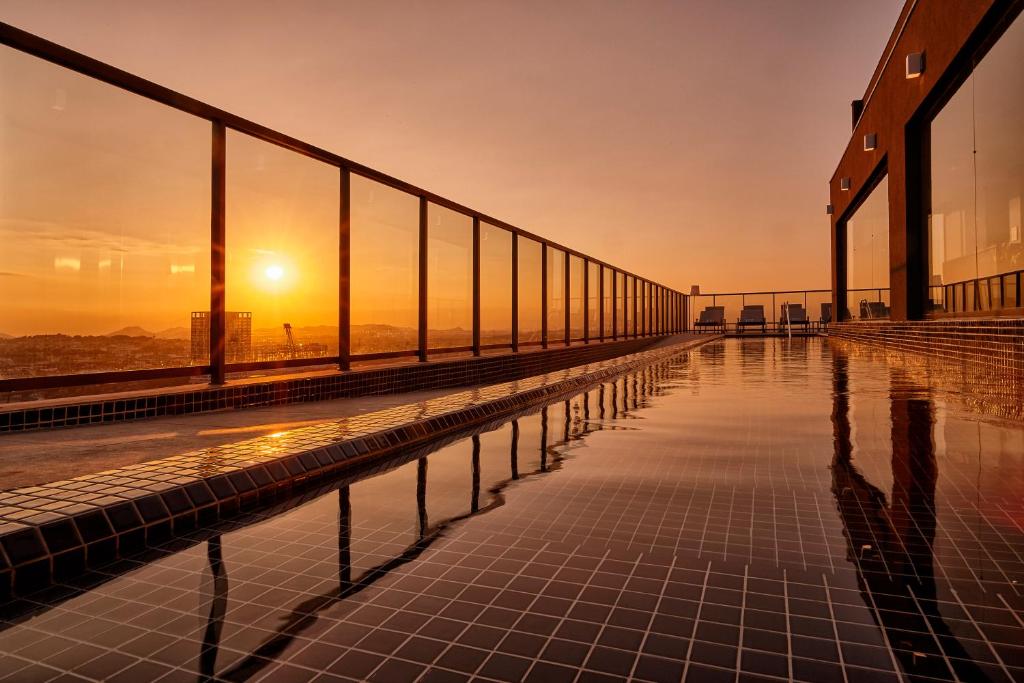 里约热内卢Intercity Rio de Janeiro Porto Maravilha的一座游泳池位于一座享有日落美景的建筑的顶部