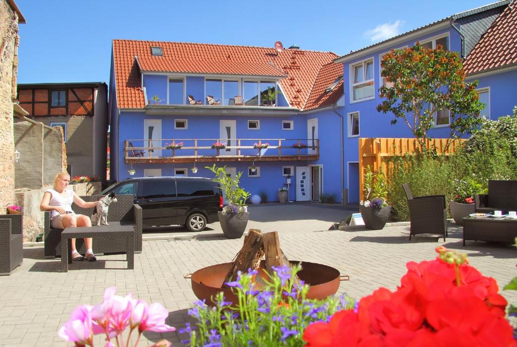 勒伯尔Ferienwohnungen Malow的坐在蓝色房子前面的长凳上的女人
