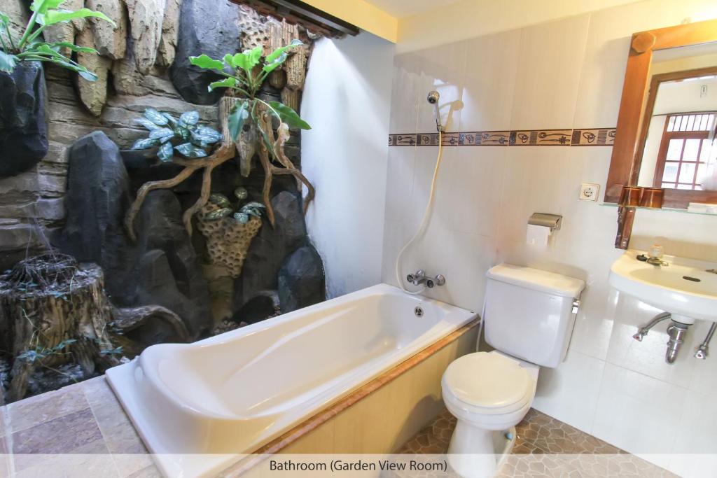 日惹都塔宾馆的带浴缸、卫生间和盥洗盆的浴室
