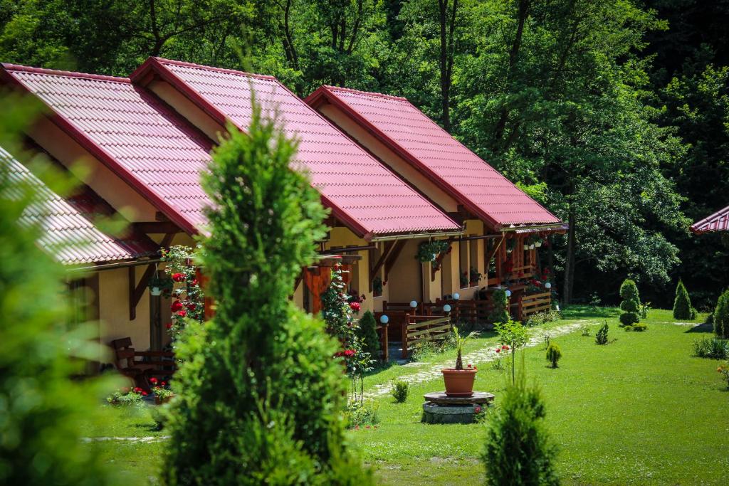 科伦德Patakmenti Panzió Spa的一座有红屋顶的房屋,位于一个树木繁茂的院子内