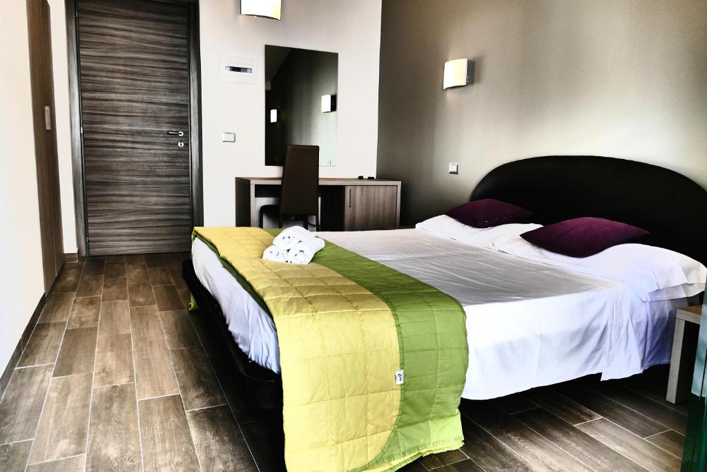 圣贝内代托-德尔特龙托Hotel Désirée的一间卧室配有一张大床,提供白色床单和紫色枕头