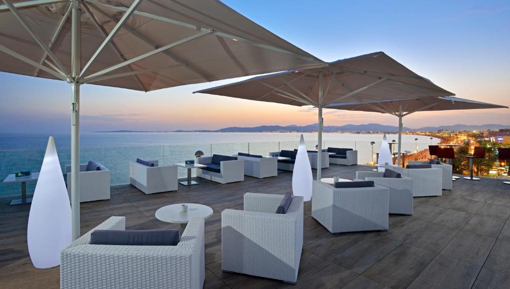 帕尔马海滩伊斯帕尼亚酒店的庭院配有白色的桌椅和遮阳伞。
