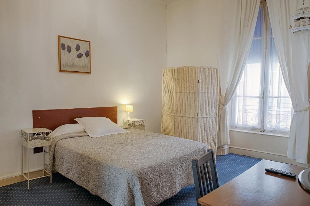里昂法库尔德酒店的一间卧室配有一张床、一张桌子和一个窗户。