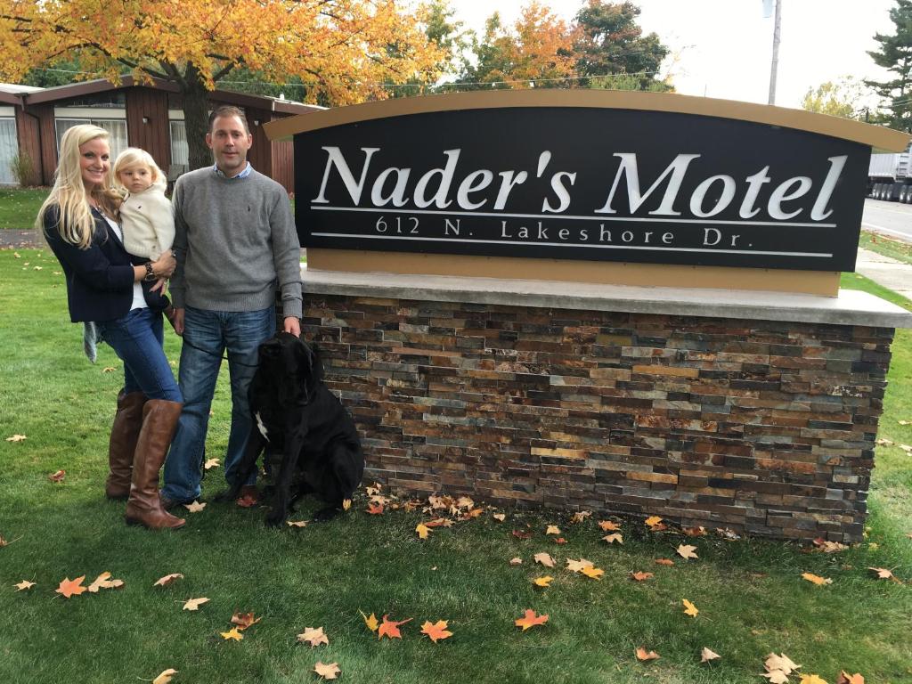 拉丁顿Nader's Motel & Suites的和狗在标志前摆姿势的家庭