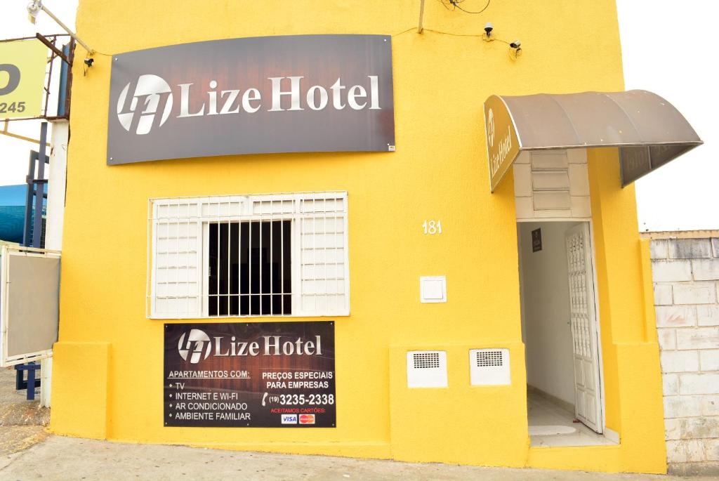 坎皮纳斯Lize Hotel的黄色的建筑,旁边标有标志