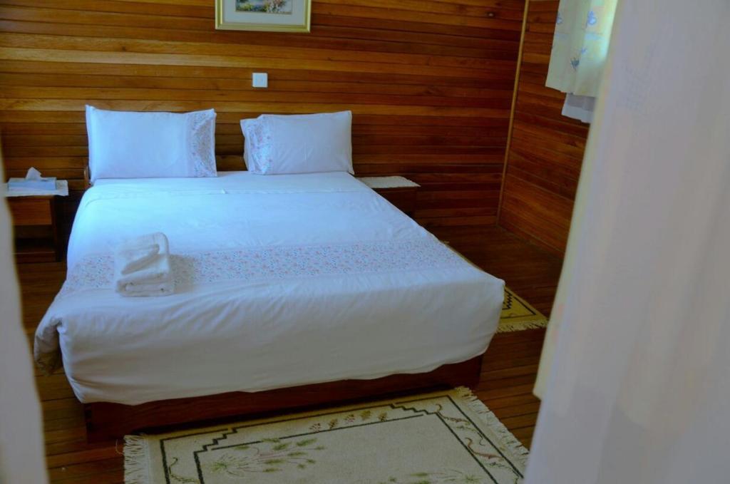 波特尔堡Bwigamiro Country Home Fort Portal的卧室配有一张白色大床和木墙