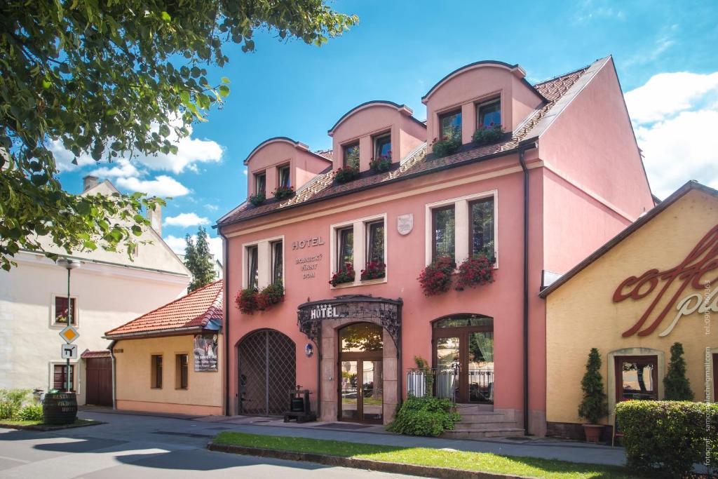 波切尼斯Hotel Bojnický vínny dom的街道边的粉红色建筑