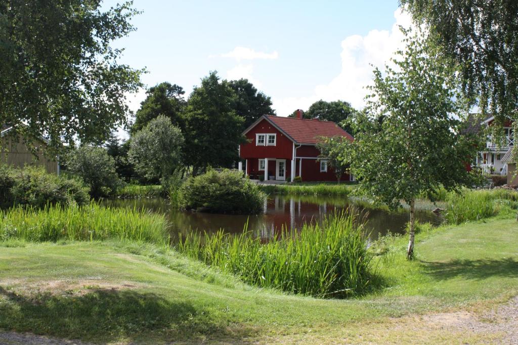 UgglumNolgårdens Turistboende的一座红色的房子,房子前面有池塘