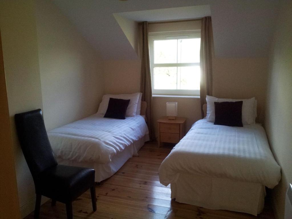 肯梅尔15 Sheen View Kenmare Co Kerry的一间卧室设有两张床、一把椅子和一个窗户。