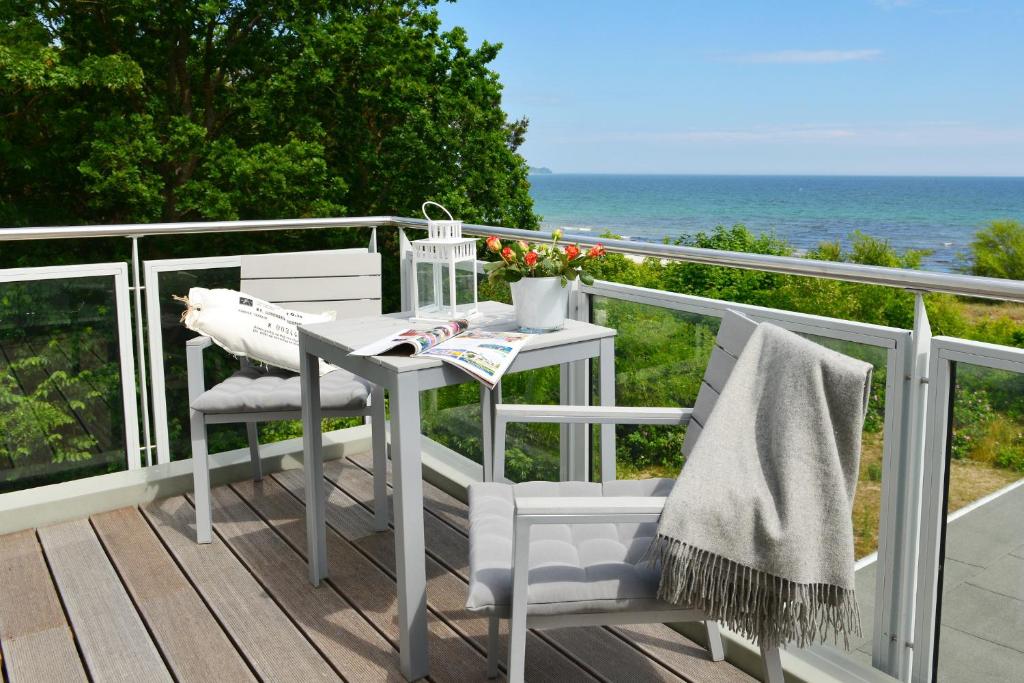 朱列斯拉赫Strandperle的阳台上配有白色的桌椅,享有海景