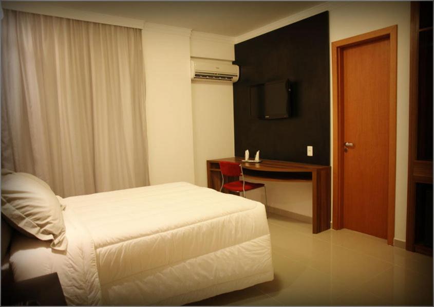 桑托斯阿兰蒂科金色公寓酒店的一间卧室配有一张床、一张书桌和一台电视