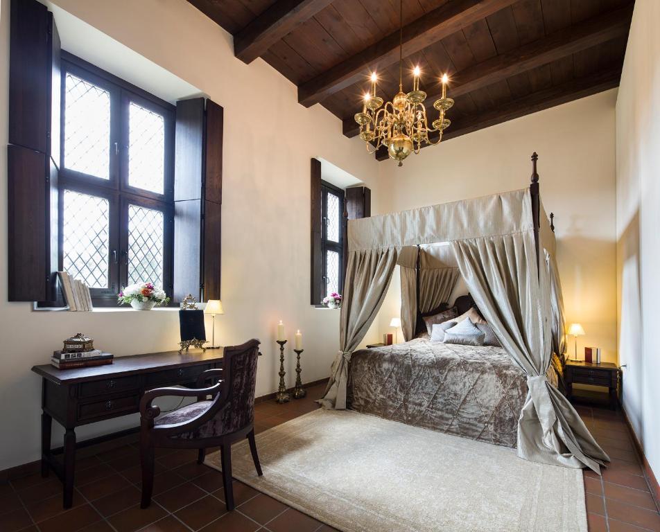 考纳斯蒙特帕斯酒店的一间卧室配有一张床、一张书桌和一个吊灯。
