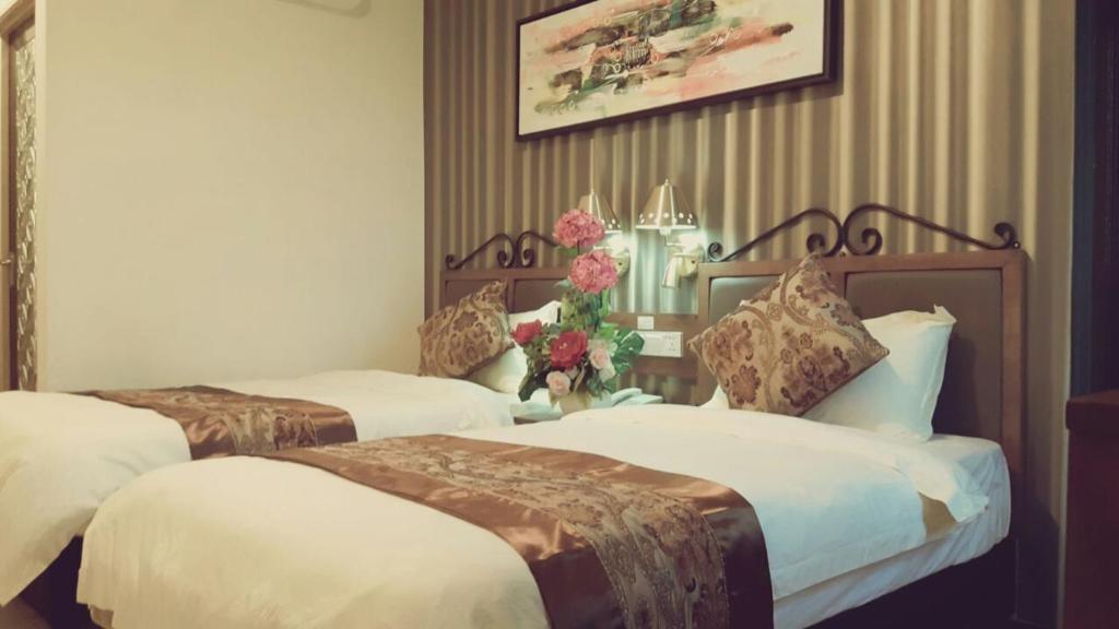 Bagan SeraiK Garden Hotel (BS)的两张床铺,位于酒店客房,墙上挂着鲜花