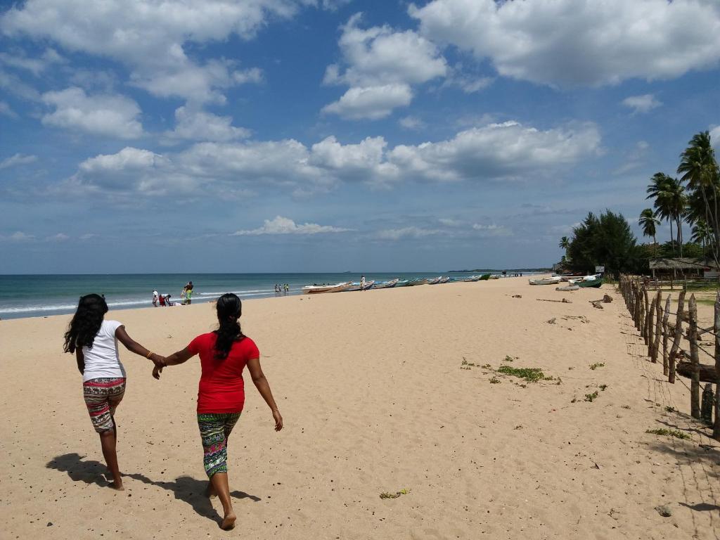 尼甘布Marine Tourist Guest House at Negombo Beach的两名妇女手持着在海滩上行走