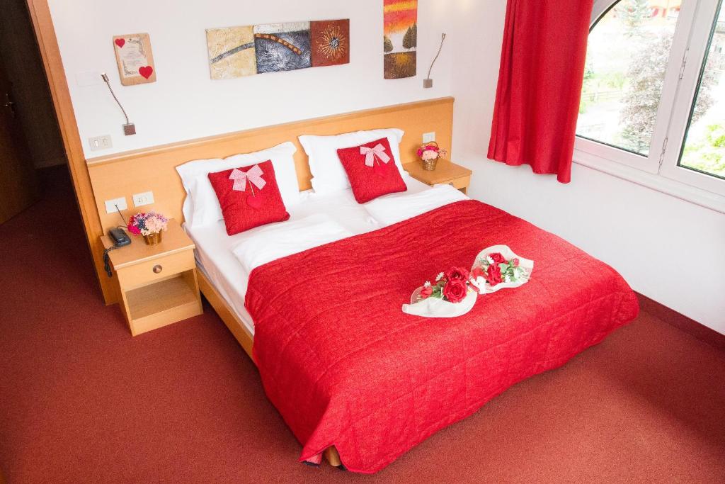 博萨迪法萨GH Hotel Piaz的一间卧室配有一张红色的床,上面放着两个托盘