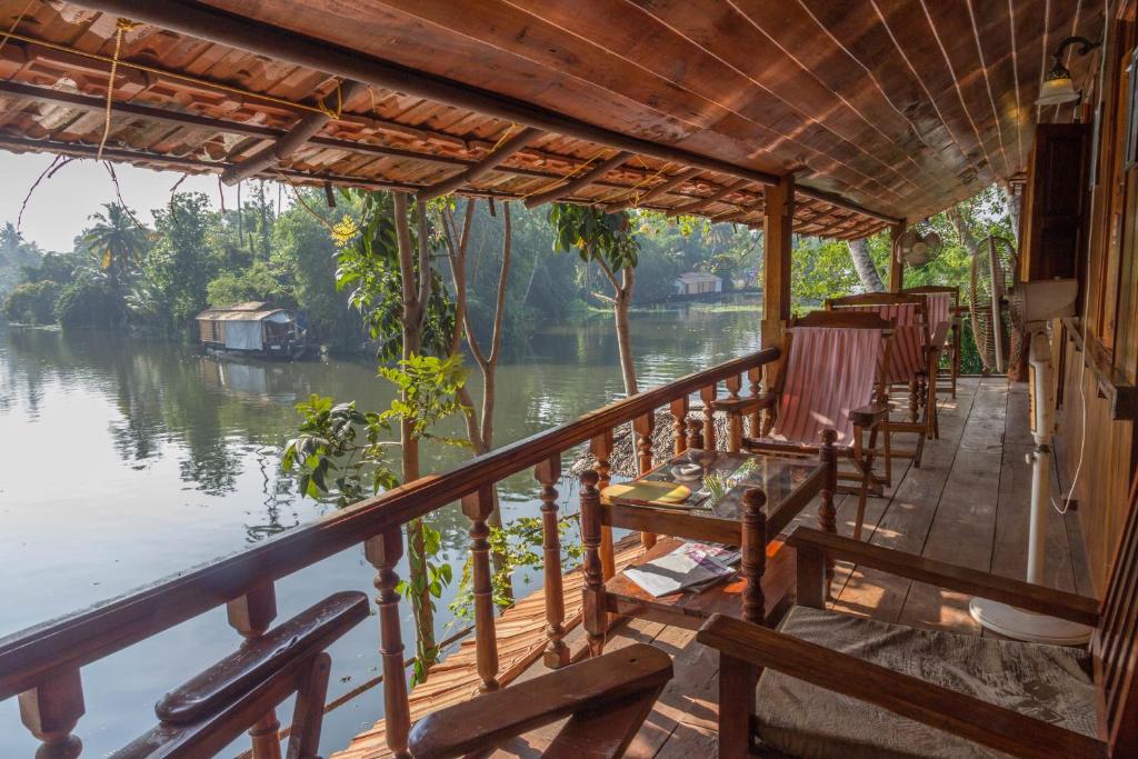阿勒皮Malayalam Lake Resort的河景门廊配有椅子