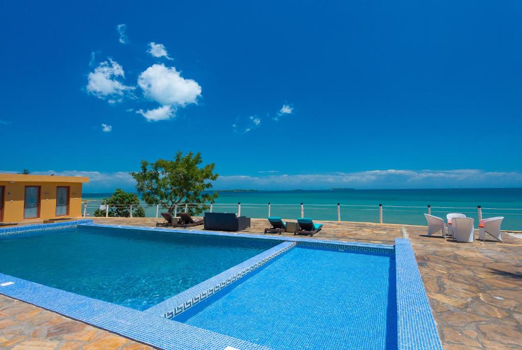 桑给巴尔金色郁金香桑给巴尔度假酒店的一个带椅子的游泳池,背景是大海