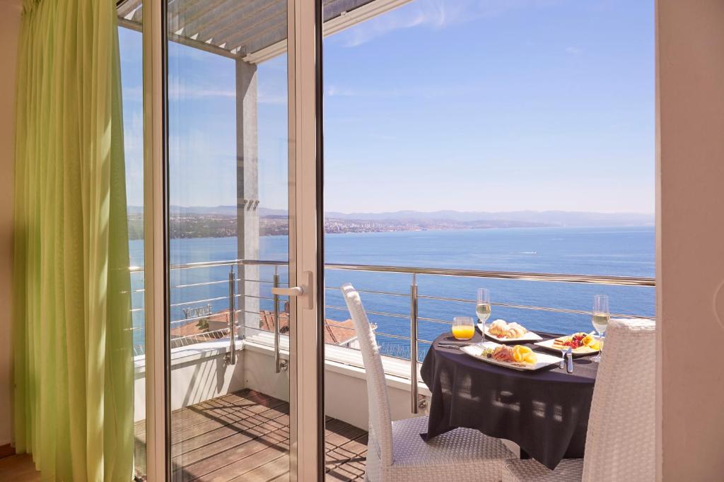 奥帕提亚ASTORIA Hotel Opatija的阳台上的餐桌和食物,享有海景