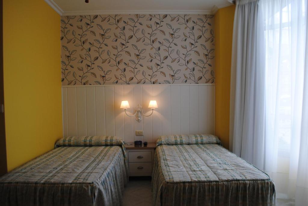 巴约讷Hostal Santa Marta Playa的配有两张床铺的黄色墙壁和窗帘